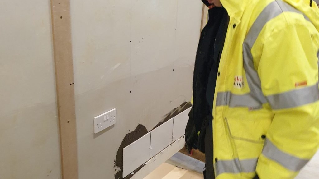 Male construction student tiling a wall close up