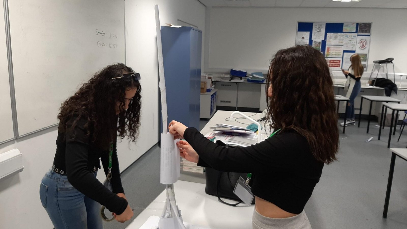 Female students taping paper statue