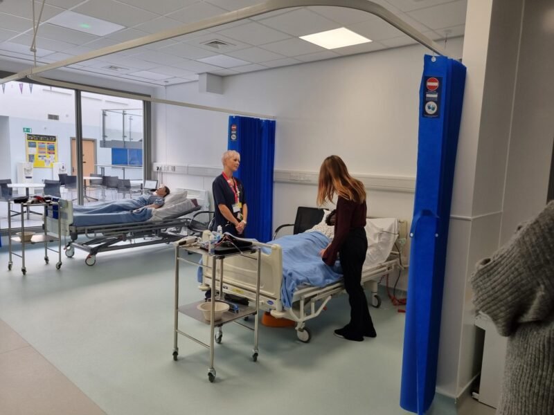 health student next to hospital bed overseen by nurse. teaching the students